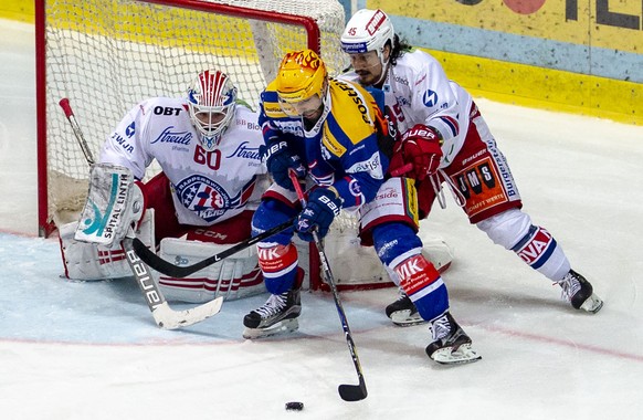 EHC Kloten Stuermer Denis Hollenstein, Mitte, gegen SC Rapperswil-Jona Lakers Torhueter Melvin Nyffeler, links, und Verteidiger Jorden Gaehler, rechts, im dritten Eishockey Spiel der Ligaqualifikation ...