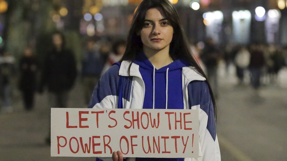 A woman shows a poster to journalists during a rally against a draft law aimed at curbing the influence of "foreign agents" near the Georgian parliament building in Tbilisi, Georgia, Thursda ...