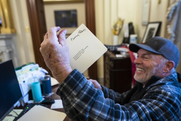 epaselect epa08923450 A supporter of US President Donald J. Trump sits on the desk of US House Speaker Nancy Pelosi, after supporters of US President Donald J. Trump breached the US Capitol security i ...