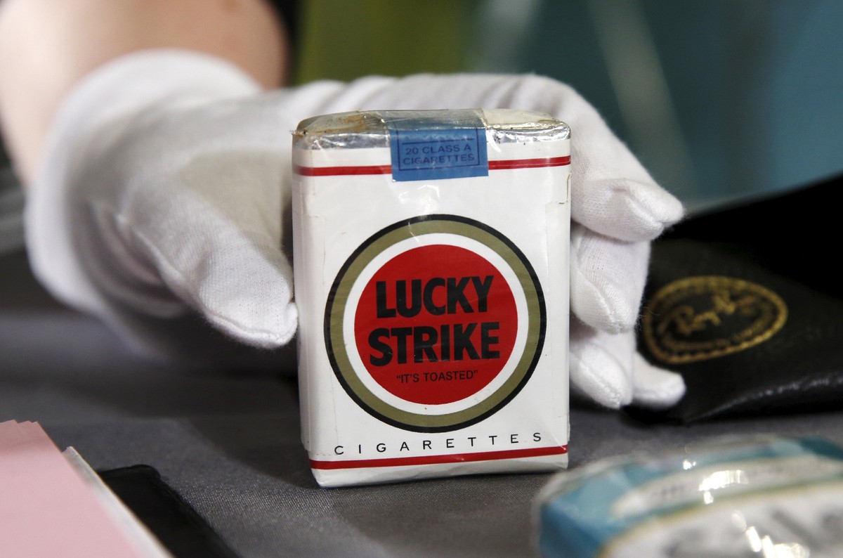 A museum worker holds a pack of Lucky Strike cigarettes used on the set of the television series "Mad Men" during a donation ceremony at the Smithsonian National Museum of American History i ...