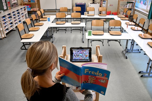 epa08947400 A teacher stands in an empty classroom and uses an iPad to teach children at home, at the closed elementary school ?Am Weyer? in Dinslaken, Germany, 18 January 2021. To slow the spread of  ...