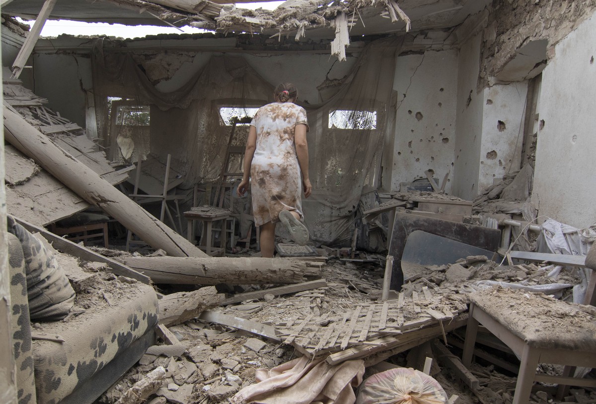 A woman visit her apartment damaged after shelling in Mariupol, Ukraine, Monday, Aug. 17, 2015. At least seven civilians and two Ukrainian troops were killed overnight today in eastern Ukraine as shel ...