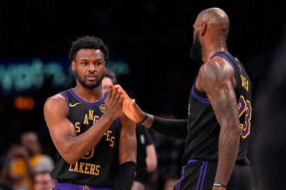 Los Angeles Lakers guard Bronny James, left, taps forward LeBron James as he comes into the game as LeBron James comes out during the second half of an NBA basketball game against the Atlanta Hawks, T ...