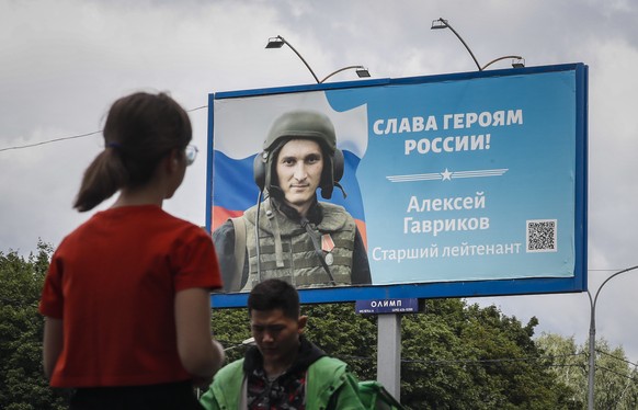 epa10082475 People walk past a billboard depicting a soldier with a slogan reading &#039;Glory to the Heroes of Russia&#039; in Moscow, Russia, 20 July 2022. On 24 February 2022 Russian troops entered ...