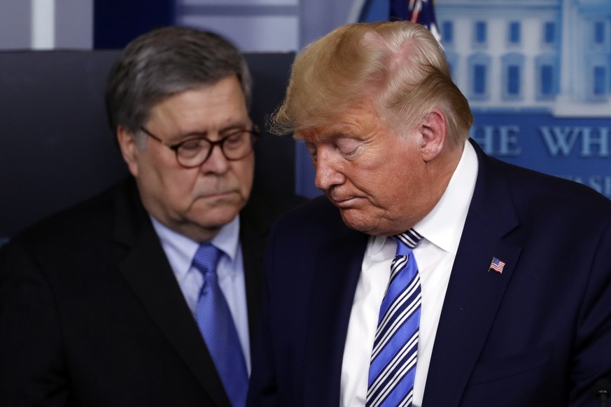 FILE - In this March 23, 2020, file photo President Donald Trump moves from the podium to allow Attorney General William Barr to speak about the coronavirus in the James Brady Briefing Room in Washing ...