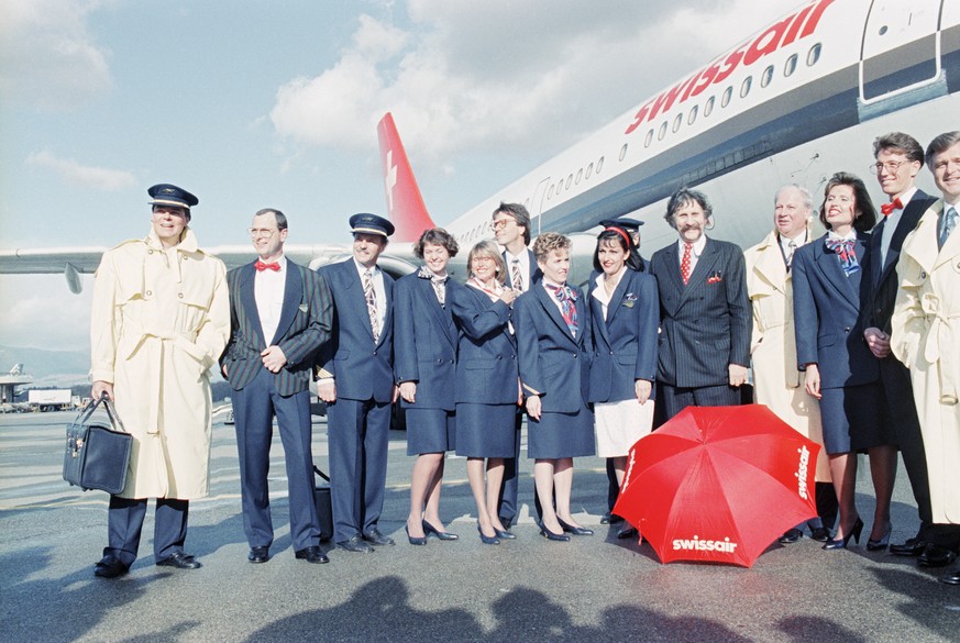 Zur selben Zeit an einem anderen Ort: Designer Luigi Colani, der Entwerfer der neuen Swissair-Uniformen, posiert im Januar 1990 am Flughafen Zürich Kloten mit von ihm ausstaffierten Piloten und Stewardessen.&nbsp;