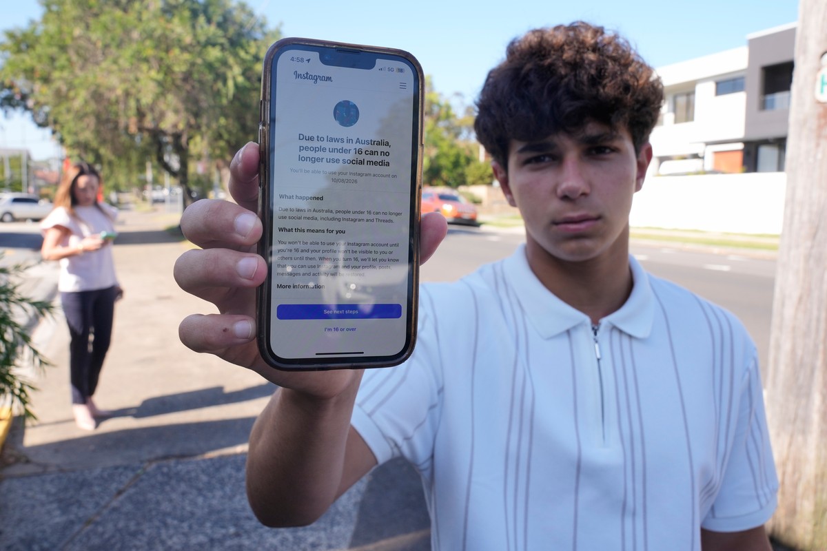 Noah Jones shows a warning on his phone that says he cannot access a social media site as his mother Renee, walks toward him in Sydney, Tuesday, Dec. 9, 2025. (AP Photo/Rick Rycroft)
Australia Social  ...