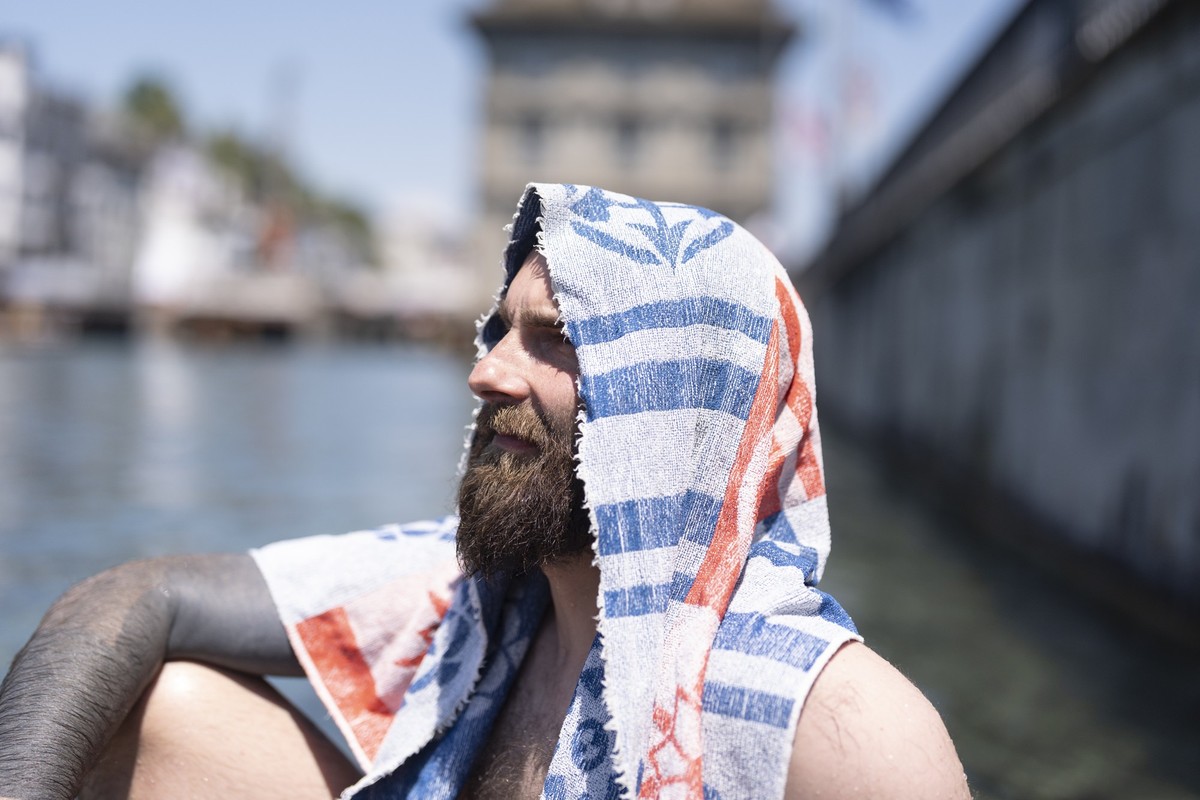 KEYPIX - Martin, Bauarbeiter von der Grossmuensterbaustelle, macht seine Mittagspause an der Limmat und schuetzt seinen Kopf gegen die Sonne mit seinem Badetuch, fotografiert am Freitag, 19. Juni 2026 ...