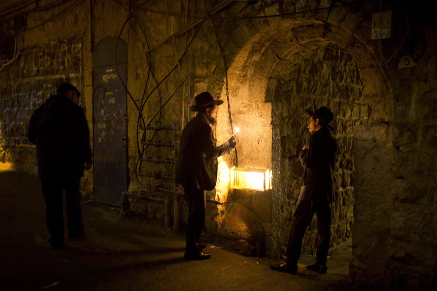 epa05690179 An Ultra-Orthodox Jew lights a Hanukkah candle during the Jewish holiday of Hanukkah in the Mea Shearim neighbourhood of Jerusalem, Israel, 28 December 2016. Hanukkah, also known as the &# ...