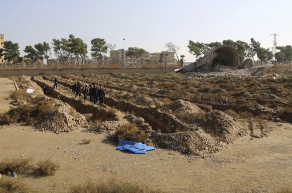 This frame grab from a video provided on Thursday, Nov. 22, 2018, shows a Syrian worker of a Raqqa group walk at the site of a mass grave believed to contain the bodies of civilians and Islamic State  ...