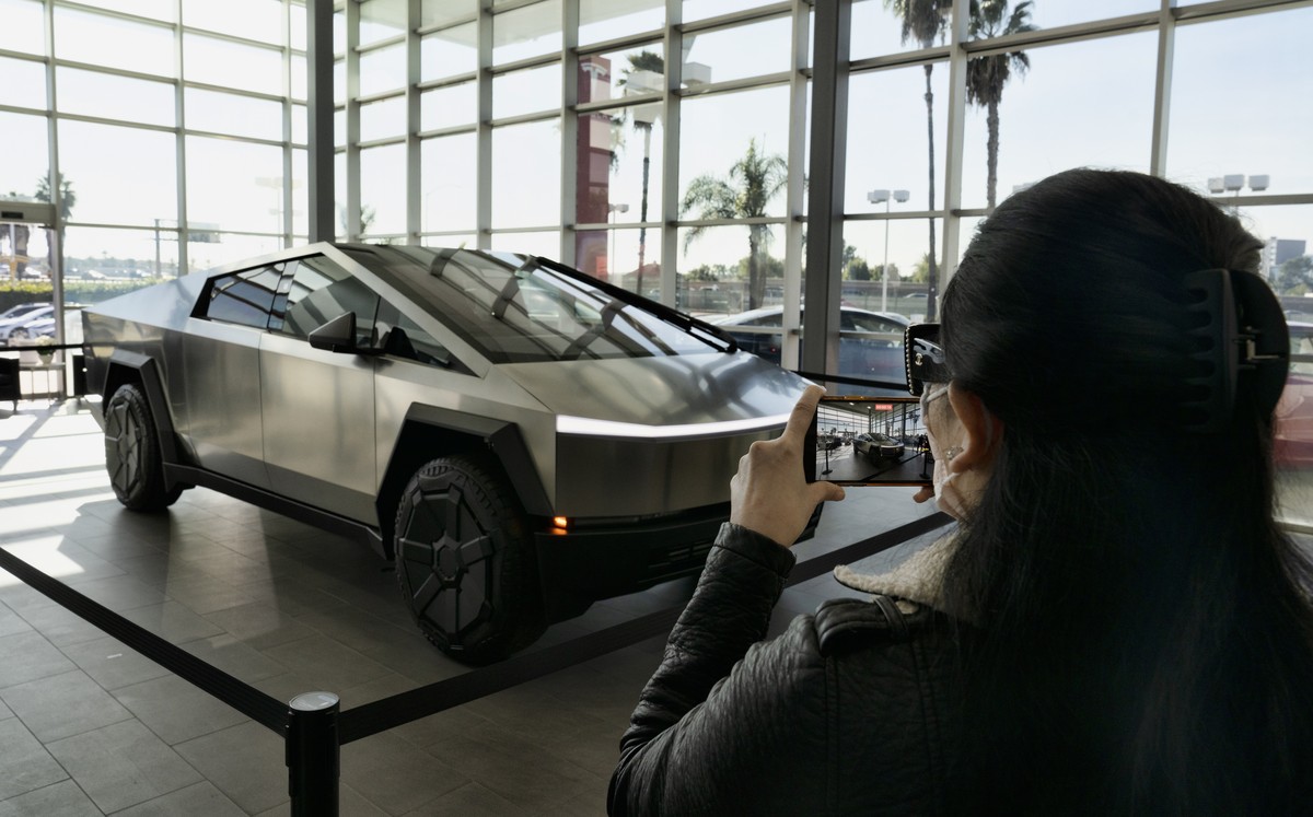 A customer takes photos of a Tesla Cybertruck on display at Tesla in Buena Park, Calif., Sunday Dec. 3, 2023. With manufacturing kinks still to be worked out, Tesla has delivered the first dozen or so ...