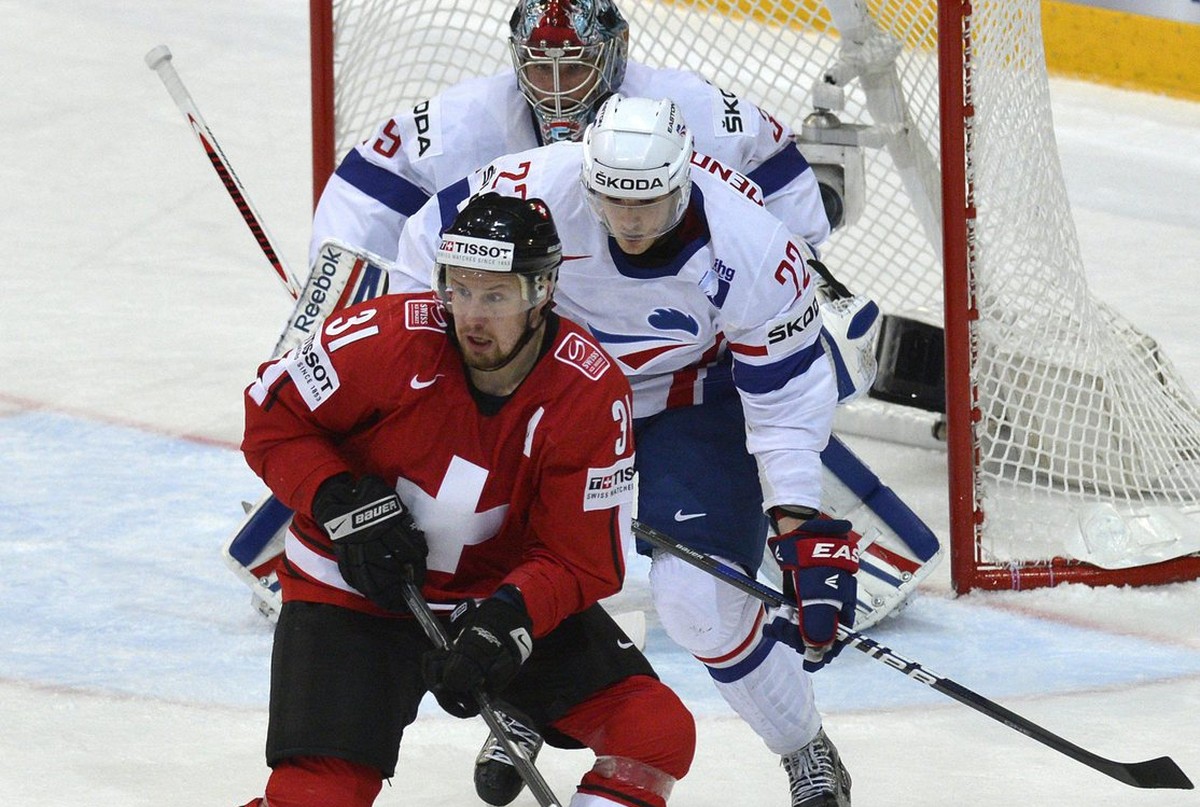 Switzerland's Mathias Seger, front, fights for the puck against France's Brian Henderson, center, and goalkeeper Christobal Huet during the Ice Hockey World Championship preliminary round gr ...
