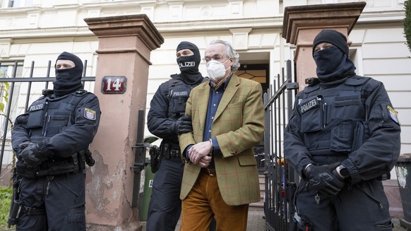 07.12.2022, Hessen, Frankfurt/Main: Bei einer Razzia gegen sogenannte «Reichsbürger» führen vermummte Polizisten, nach der Durchsuchung eines Hauses Heinrich XIII Prinz Reuß (2.v.r.) zu einem Polizeif ...