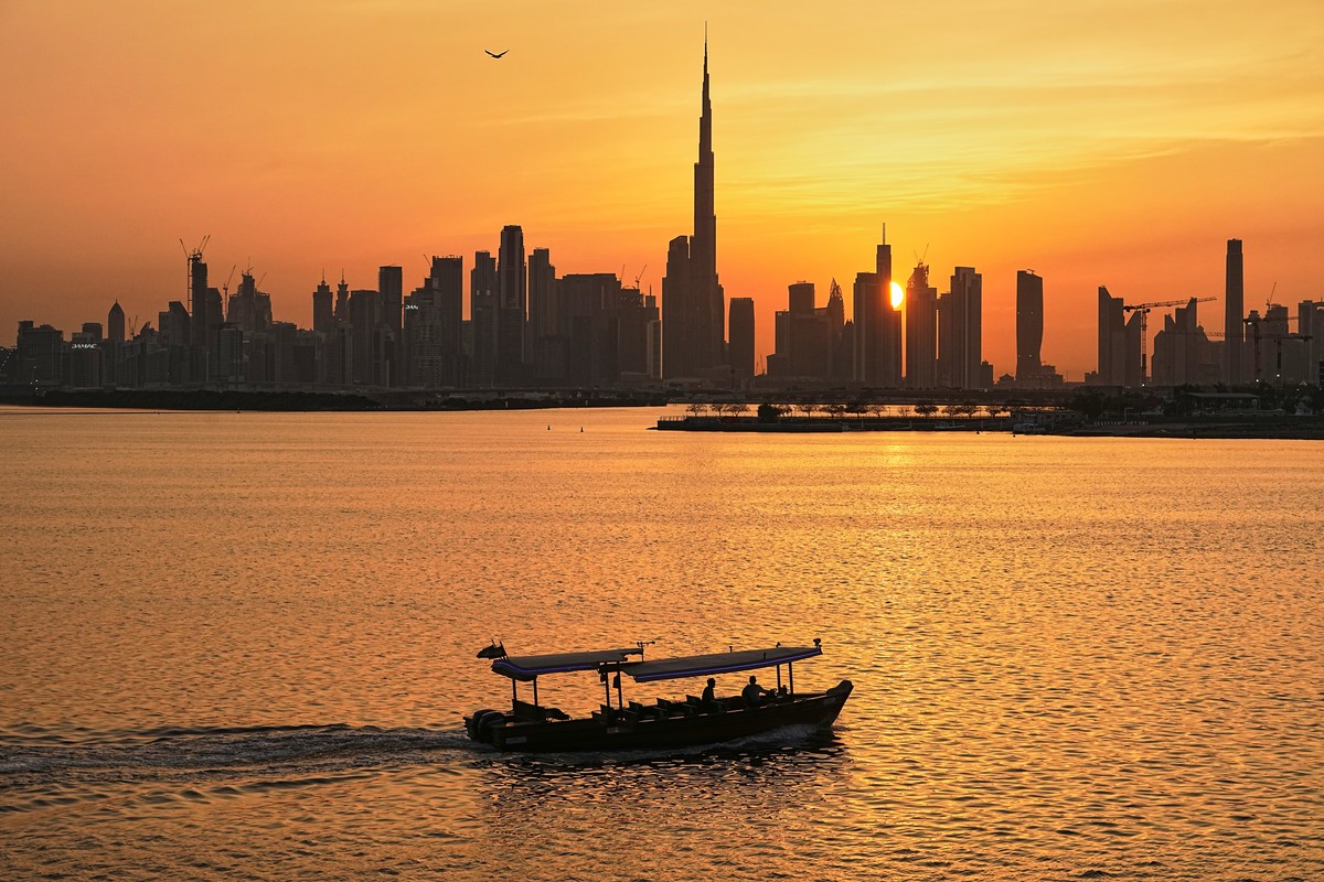 A man steers a boat during sunset, as the city skyline with Burj Khalifa is seen in the background at Dubai Creek Harbour in Dubai, United Arab Emirates, Wednesday, March 11, 2026. (AP Photo/Fatima Sh ...