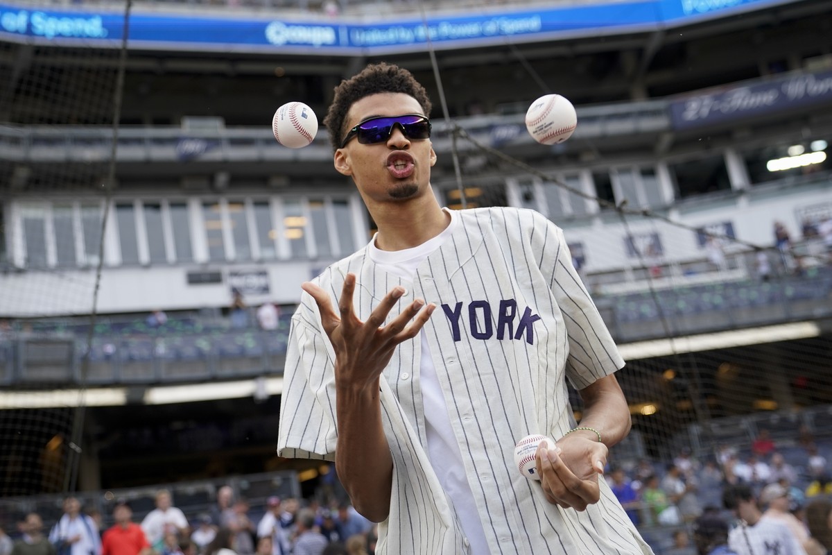 Victor Wembanyama, a projected first round 2023 NBA draft prospect, juggles baseballs before throwing the ceremonial first pitch before a baseball game between the New York Yankees and the Seattle Mar ...