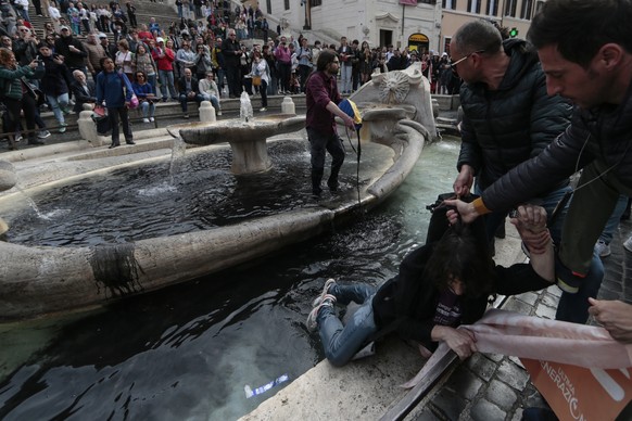 An environmental activist is removed from the &#039;&#039;Fontana della Barcaccia&#039;&#039; (Fountain of the Boat) by police as the other activist pours black paint inside the fountain during a prot ...
