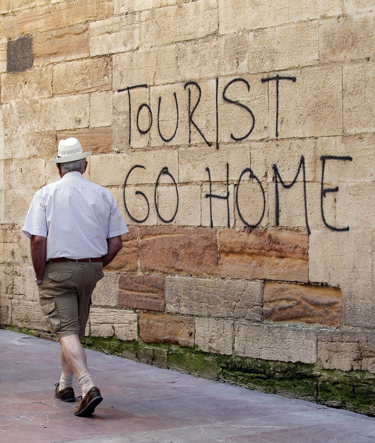 epa06124422 A man walks past a 'Tourists Go Home' graffitti on a wall close to the City Hall in Oviedo, northern Spain, 04 August 2017. Spanish Energy and Tourism Minister, Alvaro Nadal (uns ...