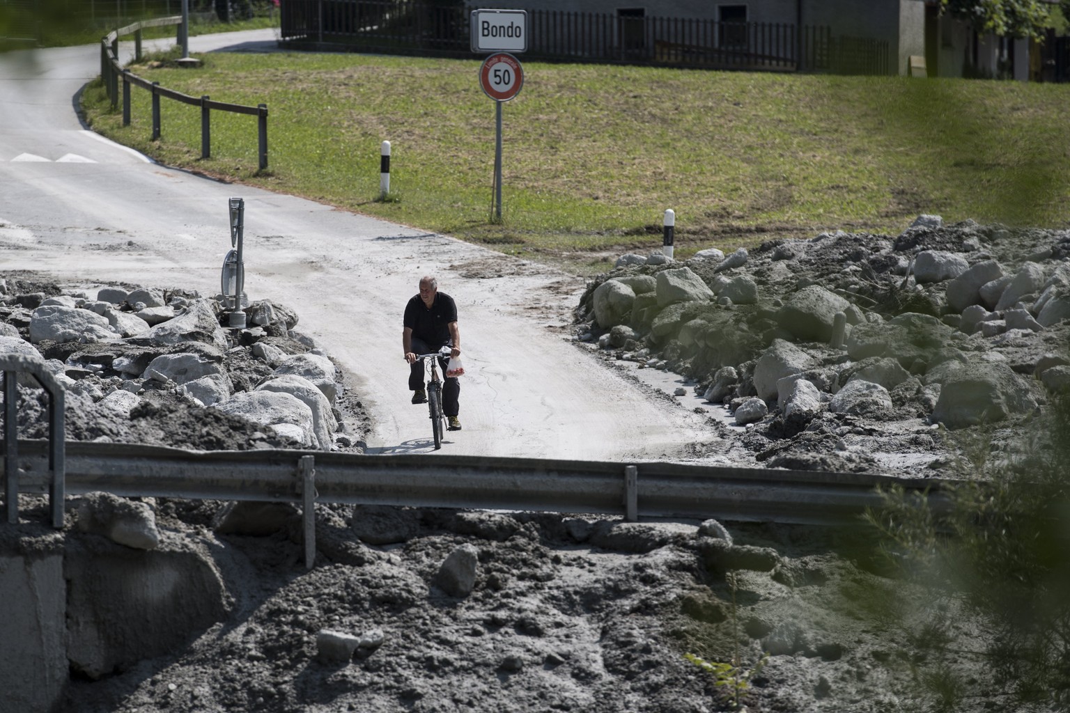 epa06161921 A man rides his bike in Bondo, Graubuenden in southern Switzerland, 25 August 2017. The village had been hit by a massive landslide on Wednesday. The main road between Stampa and Castasegn ...