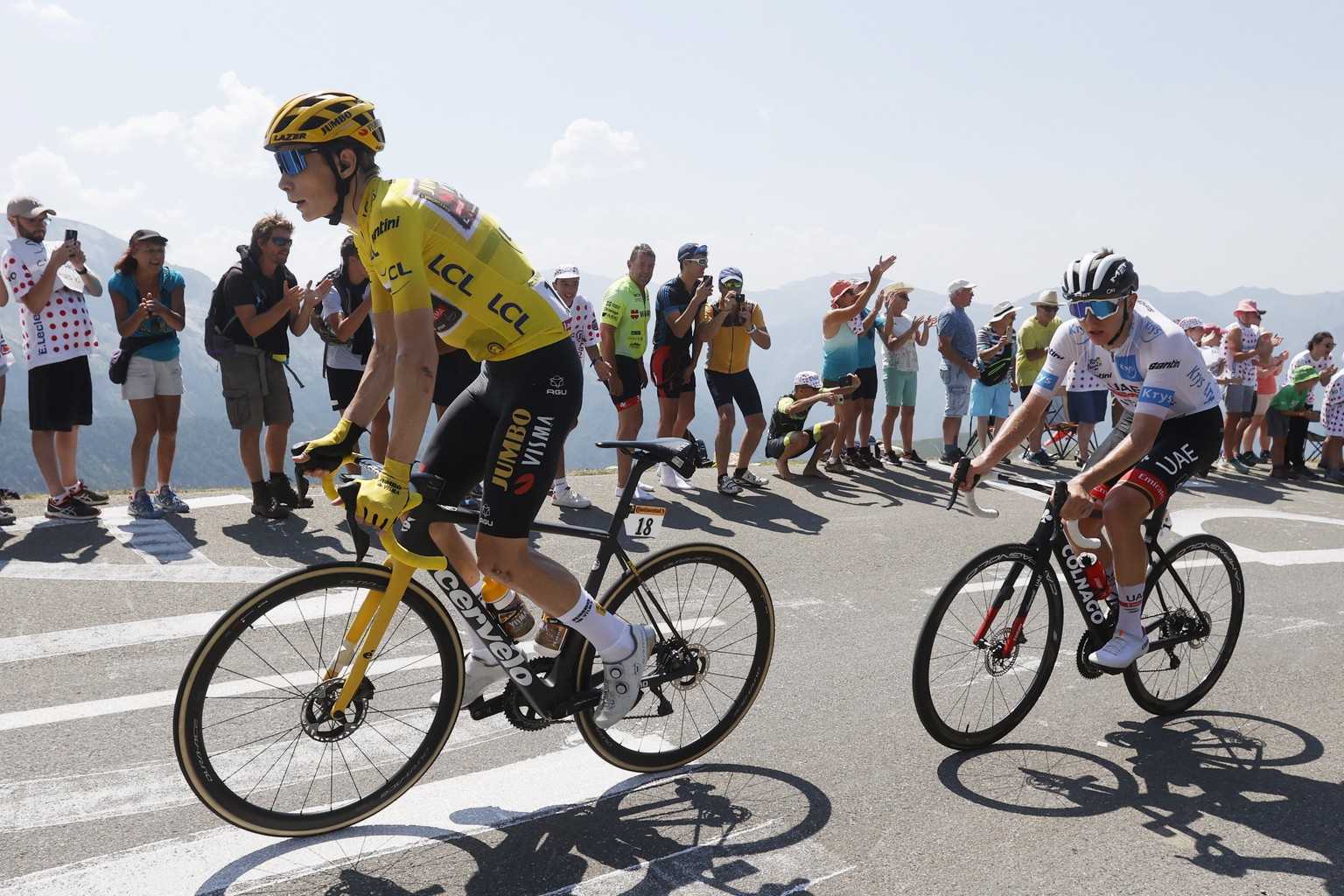 epa10084272 Spectators watch the Yellow Jersey Danish rider Jonas Vingegaard (L) of Jumbo Visma and Slovenian rider Tadej Pogacar (R) of UAE Team Emirates in action during the 18th stage of the Tour d ...