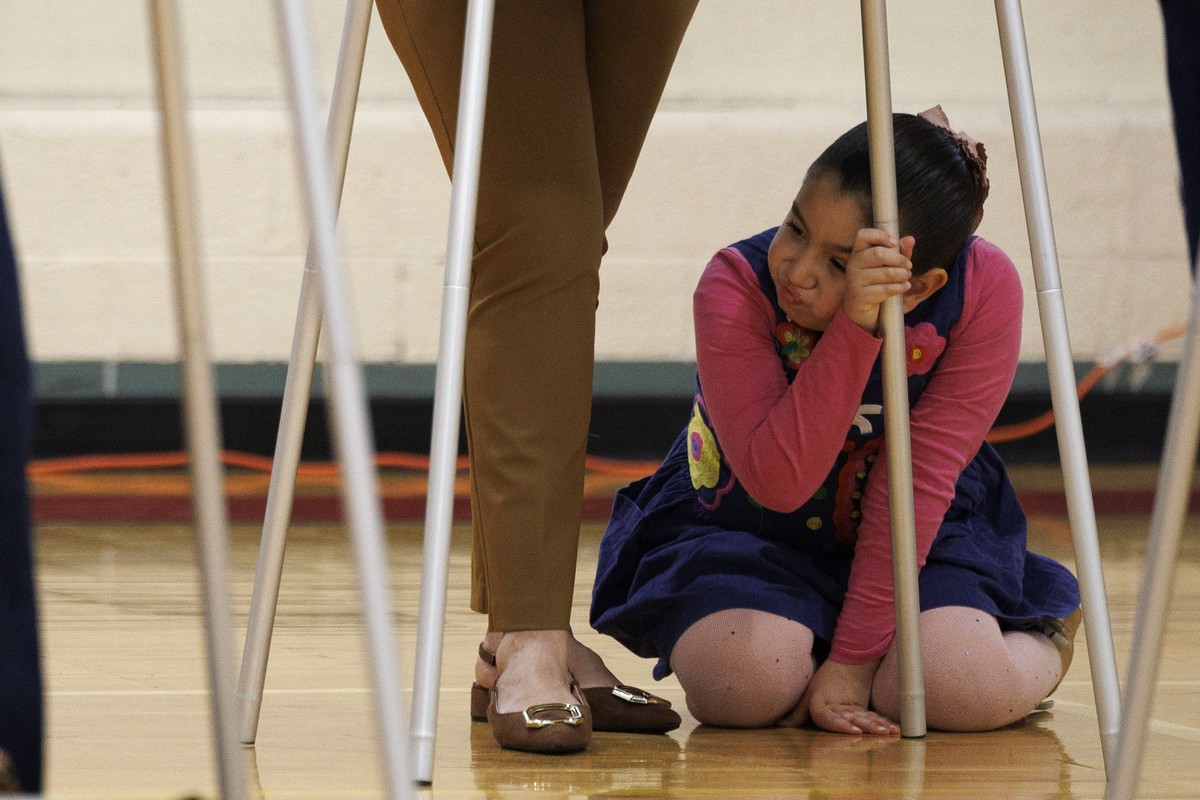 epa11703398 A girl waits on her mother to fill out a ballot at a polling location inside Dearborn STEM Middle School on Election Day in Dearborn Heights, Michigan, USA, 05 November 2024. Voters across ...