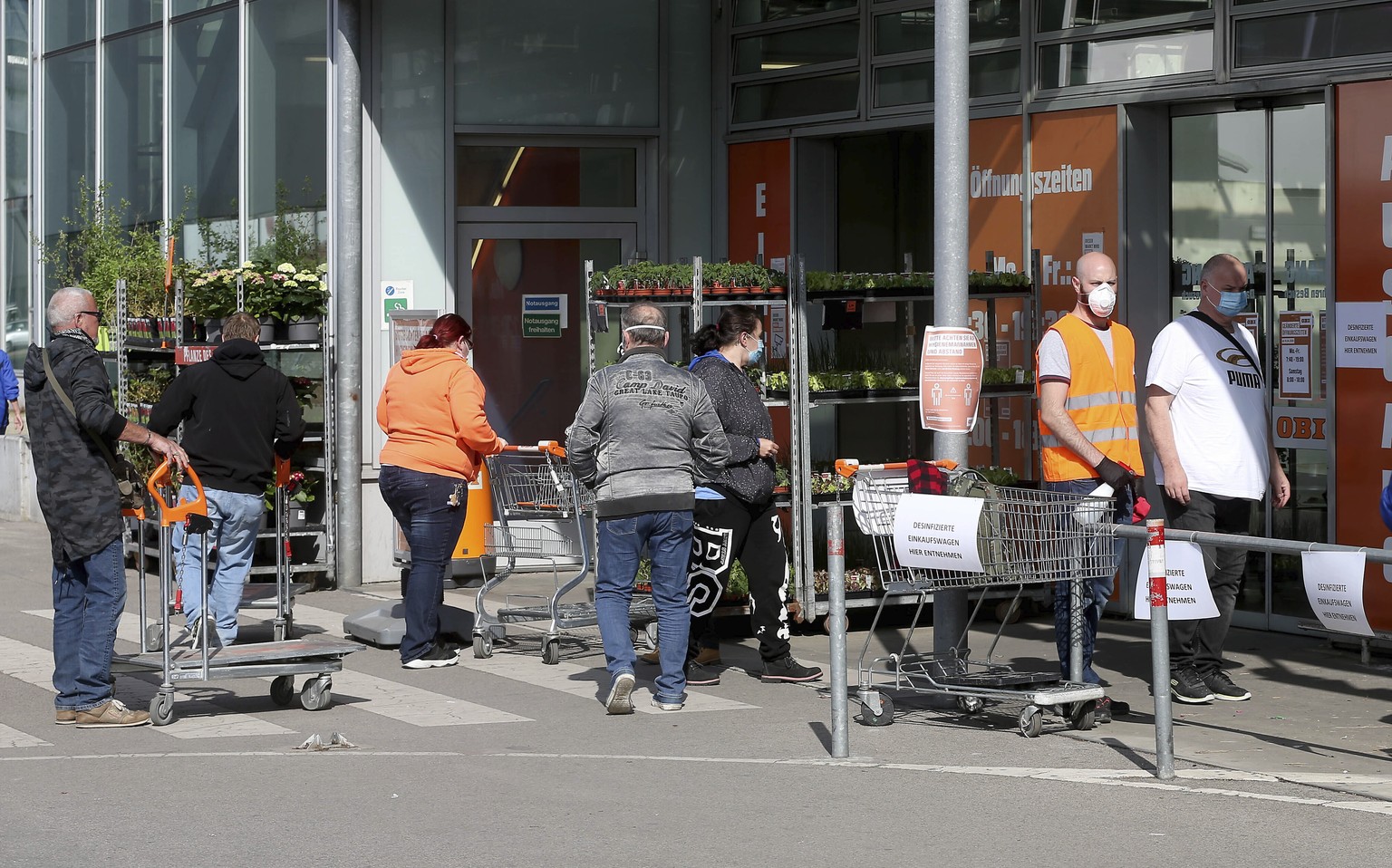 People with protective masks queue up to go in a hardware store in Vienna, Austria, Tuesday, April 14, 2020. Smaller Austrian shops may reopen with special protective measures from Tuesday on. The Aus ...