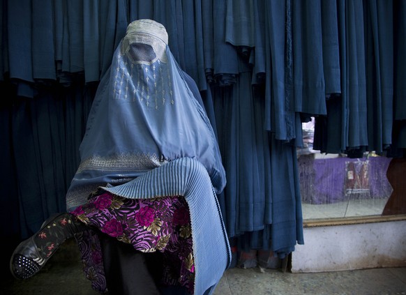 In this Thursday, April 11, 2013 photo, an Afghan woman waits to get in line to try on a new burqa at a shop in the old town of Kabul, Afghanistan. Despite advances in womens rights, Afghanistan rema ...
