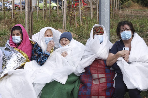 Patients sit wrapped in blankets and sheets, after a fire in the COVID-19 ICU section of the Hospital for Infectious Diseases in the Black Sea port of Constanta, Romania, Friday, Oct. 1, 2021. Authori ...