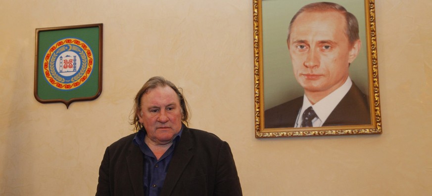 Gérard Depardieu 2013 in Grosny vor einem Konterfei von Wladimir Putin.