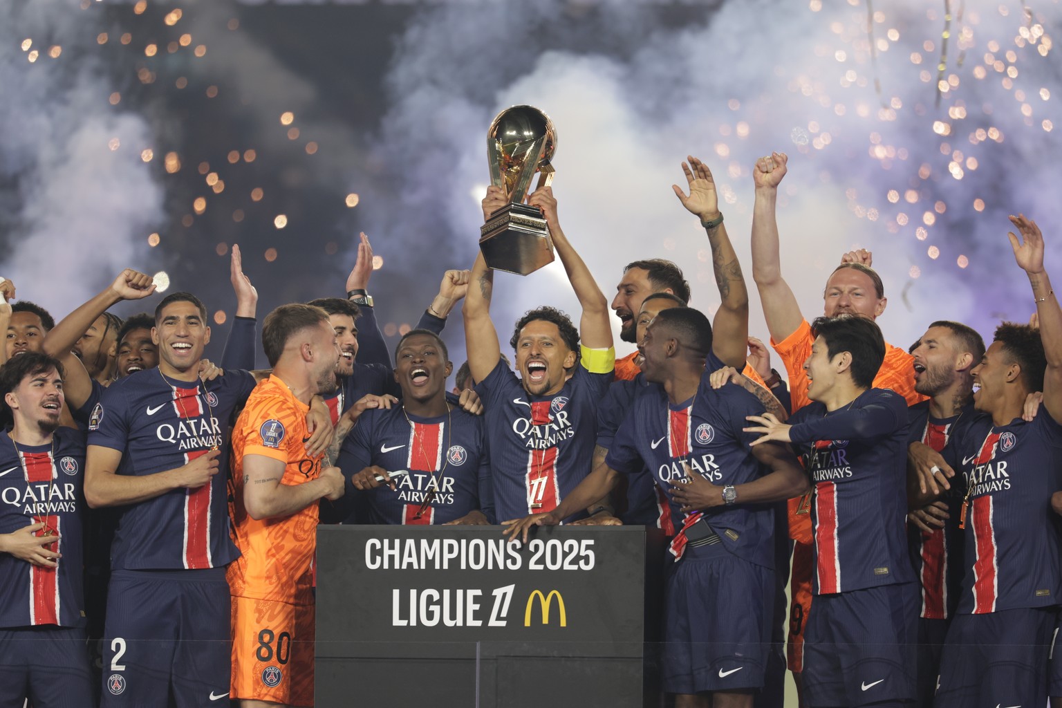 epa12111224 Marquinhos of Paris Saint Germain (C) lifts the French championship trophy after the French Ligue 1 soccer match between Paris Saint-Germain and AJ Auxerre in Paris, France, 17 May 2025. E ...