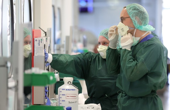 epa08336797 Medical staff put on protective clothing before treating a French patient at the intensive care unit of the University Hospital in Essen, Germany, 01 April 2020. The University Hospital Es ...