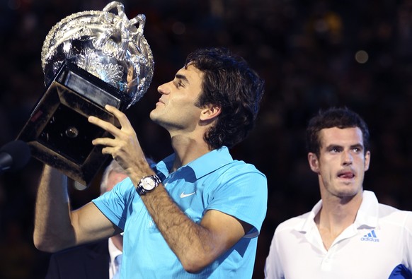 Roger Federer of Switzerland, left, holds up the trophy during the awarding ceremony, after beating Andy Murray of Britain, right, to win the Men's singles final match at the Australian Open tenn ...