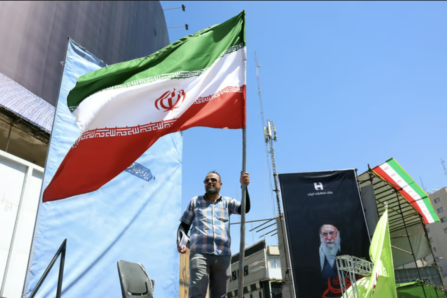 Ein Iraner mit der Nationalflagge vor einem Plakat des getöteten Revolutionsführers Ali Khamenei in Teheran.