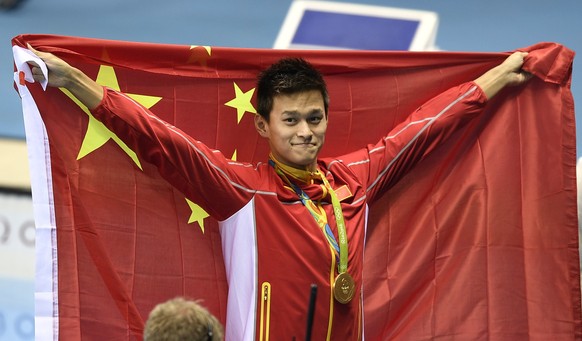 China&#039;s Sun Yang celebrates with his country&#039;s flag after winning the gold medal in the men&#039;s 200-meter freestyle final during the swimming competitions at the 2016 Summer Olympics, Mon ...