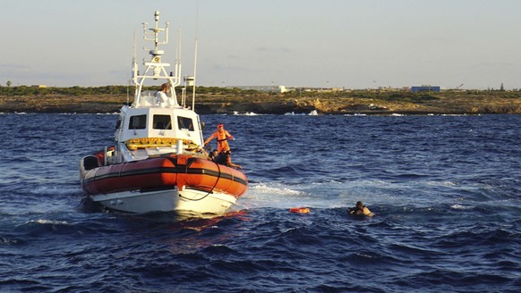 FILE - A man who threw himself in the water from the Open Arms vessel, is intercepted by the Italian Coast guards as he tried to swim to the island of Lampedusa, southern Italy, Tuesday, Aug. 20, 2019 ...