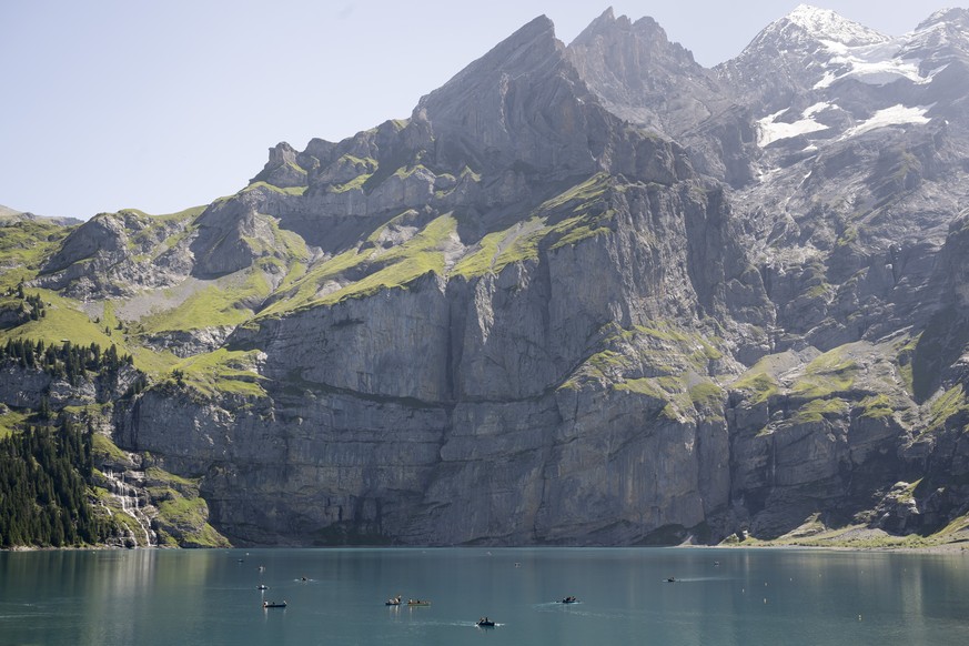 People are rowing boats on the lake of Oeschinen &quot;Oeschinensee&quot; (1578 meters above sea) and the mountains, during a very hot summer day, above Kandersteg, in the Bernese Oberland, this Augus ...