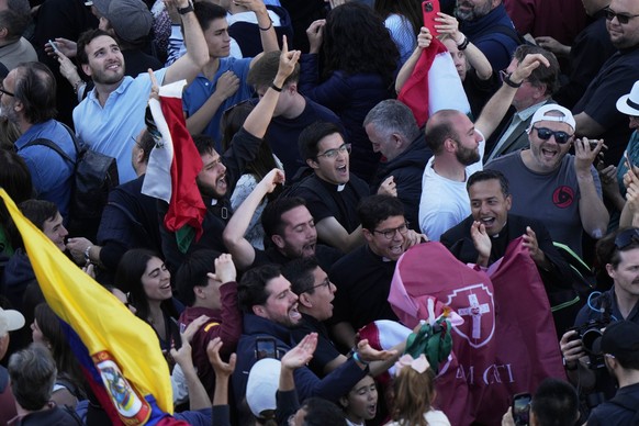 People react as white smoke billows from the chimney of the Sistine Chapel where 133 cardinals are gathering on the second day of the conclave to elect a successor to late Pope Francis, at the Vatican ...
