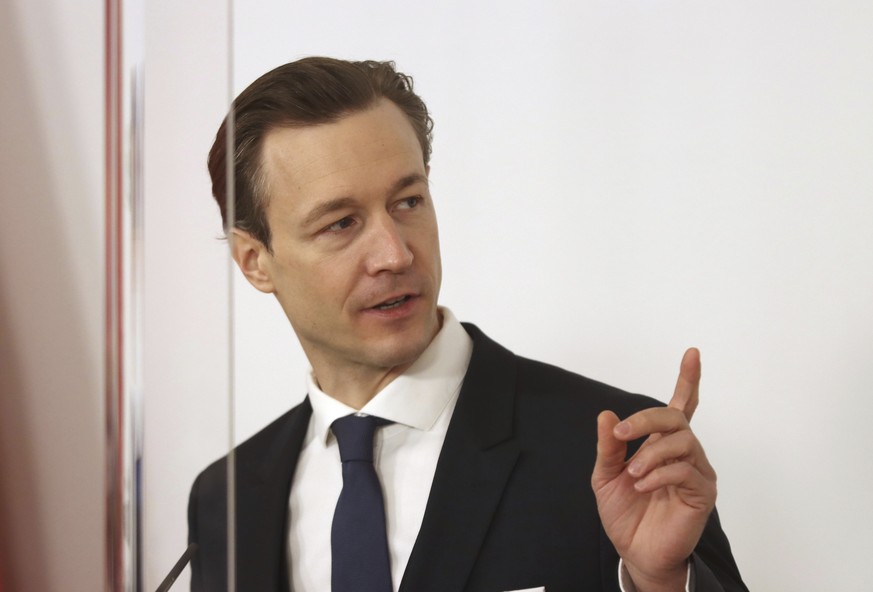 Austrian Finance Minister Gernot Bluemel speaks behind plexiglass shields during a press conference at the federal chancellery in Vienna, Austria, Tuesday, Feb. 16, 2021. (AP Photo/Ronald Zak)