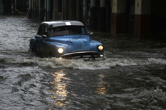 A person drives a classic American car through a street flooded by heavy rains, in Havana, Cuba, Friday, June 3, 2022. Heavy rains have drenched Cuba with almost non-stop rain for the last 24 hours as ...