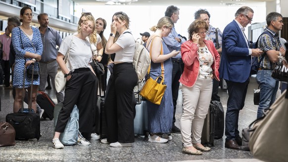 Fluggaeste warten vor einer Anzeigetafel am Mittwoch, 15. Juni 2022, auf dem Flughafen in Zuerich. Wegen einer Informatikpanne von Skyguide sind die Flughaefen Zuerich und Genf derzeit lahmgelegt. Es  ...