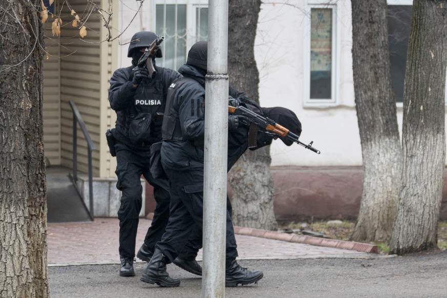 An armed riot police officer, left, shoots into the air to drive away journalists as he and his colleague detain a protester during a security anti-terrorists operation in a street after clashes in Al ...