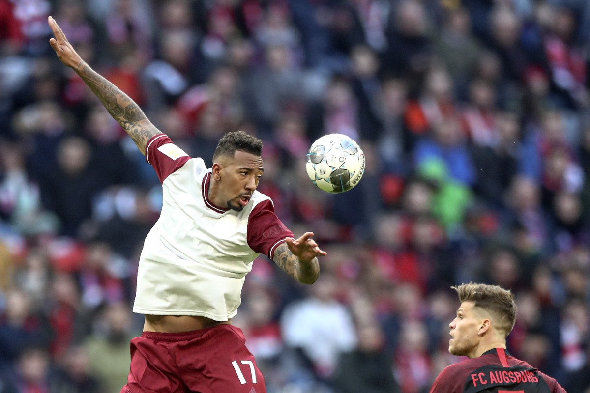 Bayern's Jerome Boateng jumps for a header next to Augsburg's Florian Niederlechner during the German Bundesliga soccer match between FC Bayern Munich and FC Augsburg in Munich, Germany, Sun ...