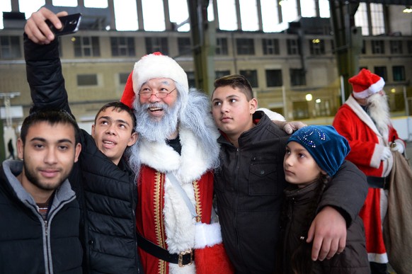 epa05680906 A man dressed as Santa Claus takes a selfie with refugee children at the refugee shelter at Tempelhof airport in Berlin, Germany, 18 December 2016. EPA/MAURIZIO GAMBARINI