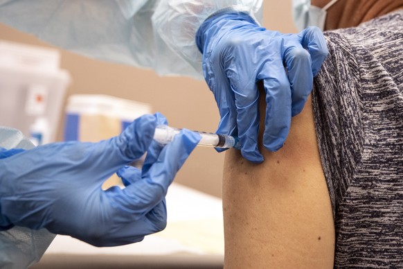 epa08746325 Modesto (R) receives a flu vaccine at a free mobile clinic in Lakewood, California, USA, 14 October 2020. Flu vaccine manufacturers have increased production in anticipation of this year&# ...