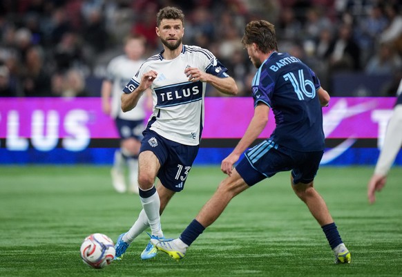 Vancouver Whitecaps' Thomas Muller (13) passes the ball past Sporting Kansas City's Jacob Bartlett (16) during the second half of an MLS soccer match, in Vancouver, British Columbia, Friday, ...