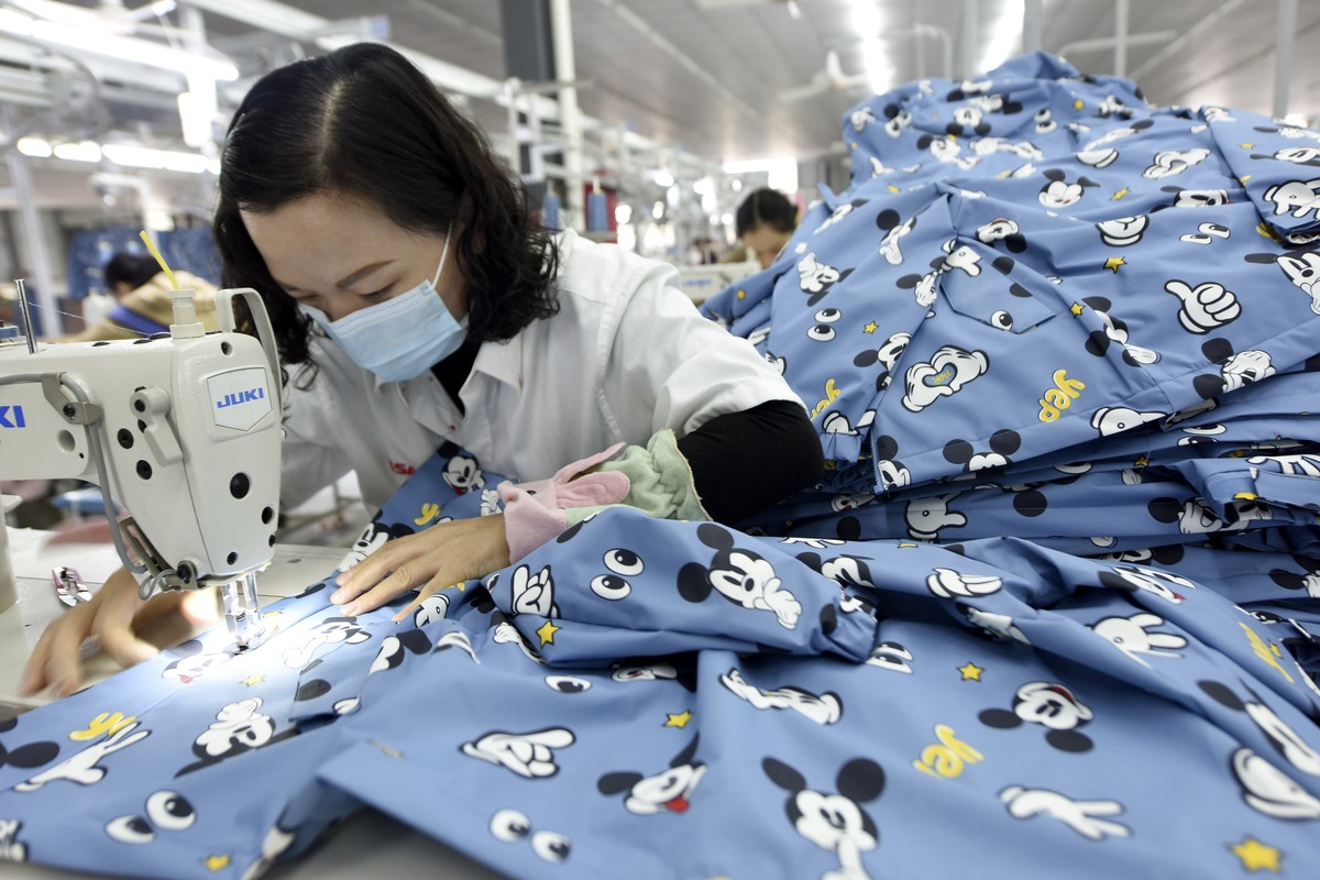 An employee wearing a face mask to protect herself against the coronavirus stitches clothing for export at a factory in Donghai county in eastern China's Jiangsu Province, Tuesday, Oct. 27, 2020. ...