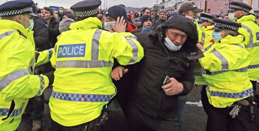 Truck drivers argue with police holding them back at the entrance to the Port of Dover, in Kent, England, Wednesday Dec. 23, 2020. Freight from Britain and passengers with a negative virus test began  ...