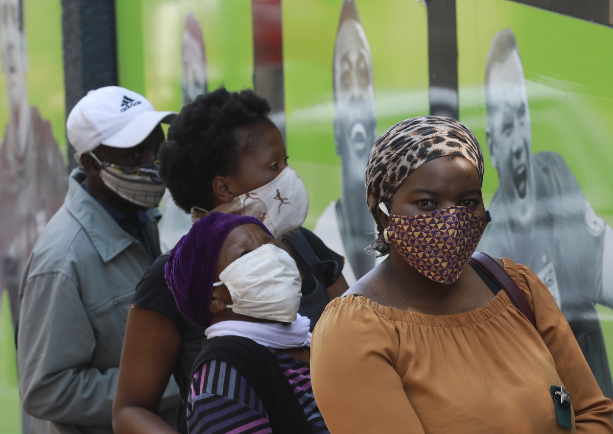 People wearing face masks queue at a South African Social Security Agency (SASSA) to collect their government grant in Cape Town South Africa, Monday, May 11, 2020. South Africa's Western Cape pr ...