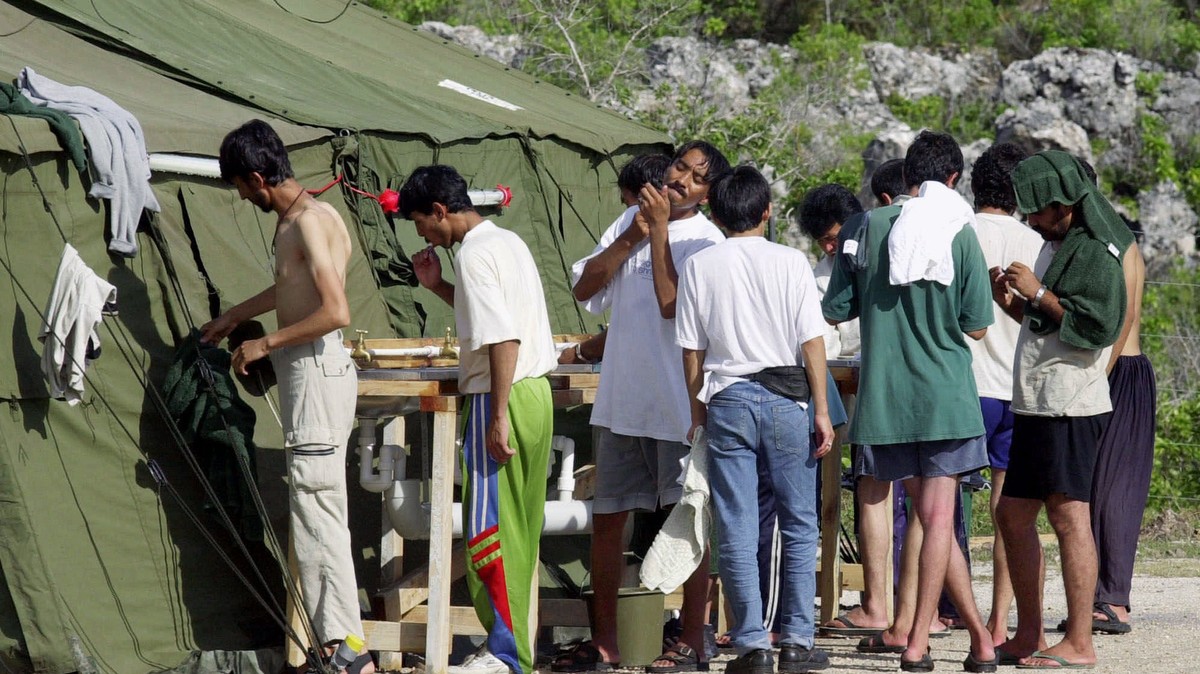 FILE - In this Sept. 21, 2001, file photo, men shave, brush their teeth and prepare for the day at a refugee camp on the Island of Nauru. The United States and Australia are close to announcing a deal ...