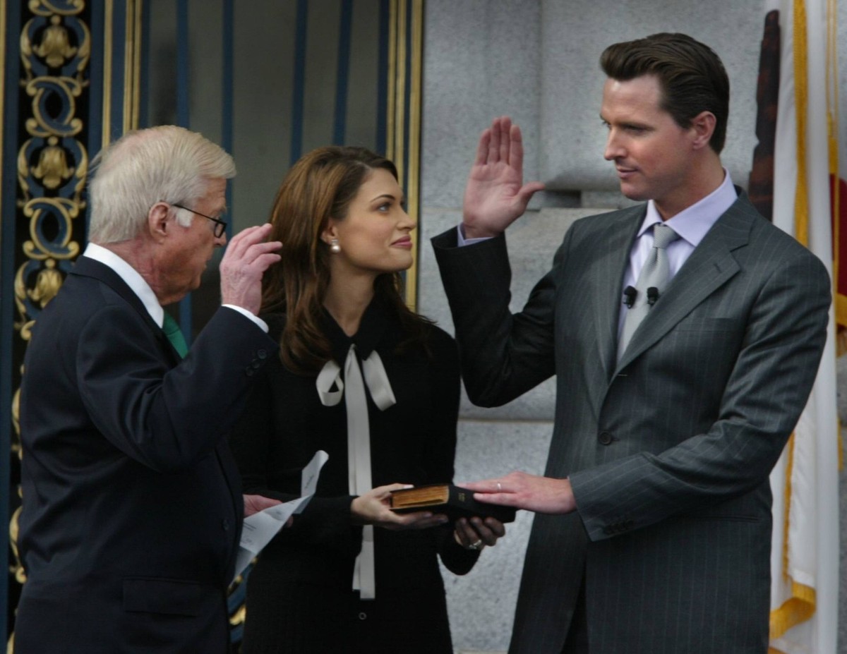 With his hand on the bible, Gavin Christopher Newsom takes the oath of office with Judge William Newson his father giving the oath, as wife Kimberly Guilfoyle Newsom looks on. Picture taken on the fro ...