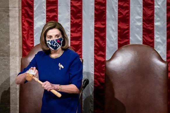 epa08923258 House Speaker Nancy Pelosi sanitizes the gavel after Vice President Mike Pence walked off the dais during a Joint session of Congress to certify the 2020 Electoral College results on Capit ...